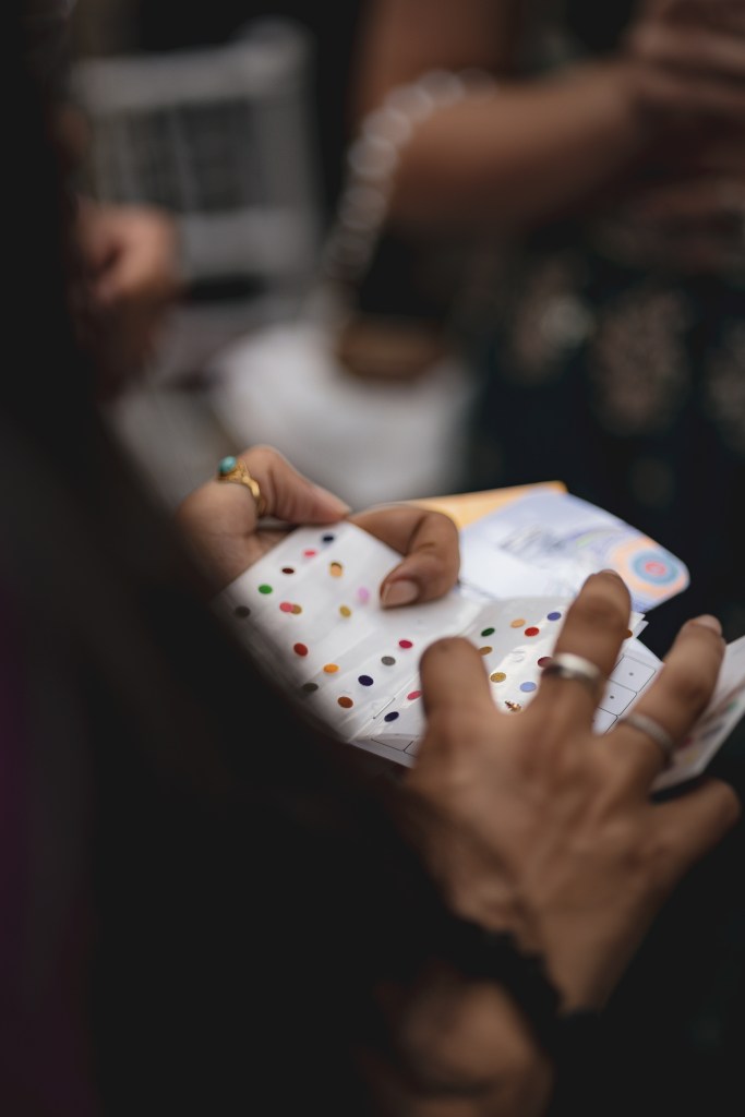 Une main tenant un livre ou un carnet ouvert contenant des échantillons de couleurs ou de points colorés.